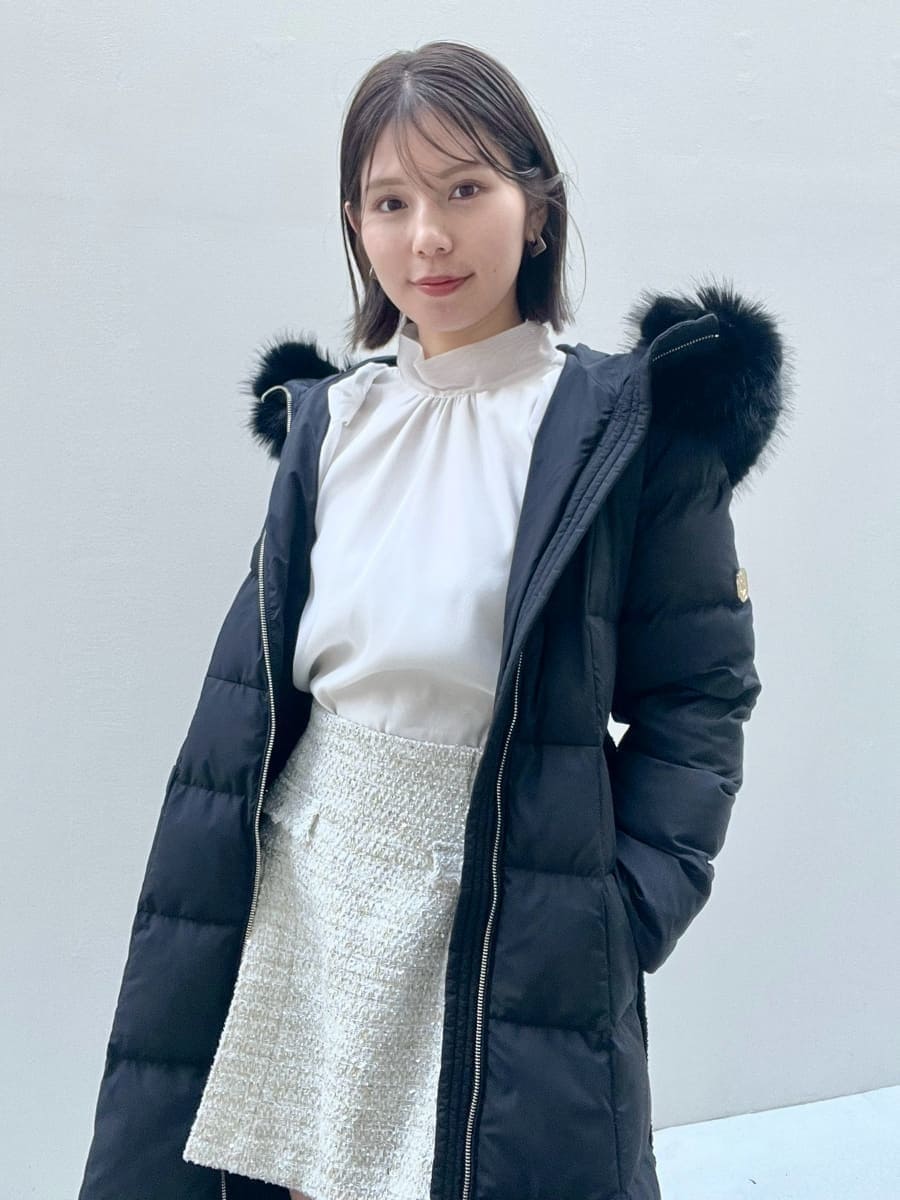 ホワイト系のスカート、ブラック系のブーツ、ブラック系のダウンジャケット/コートを着用したレディースの冬コーディネートの7枚目の写真