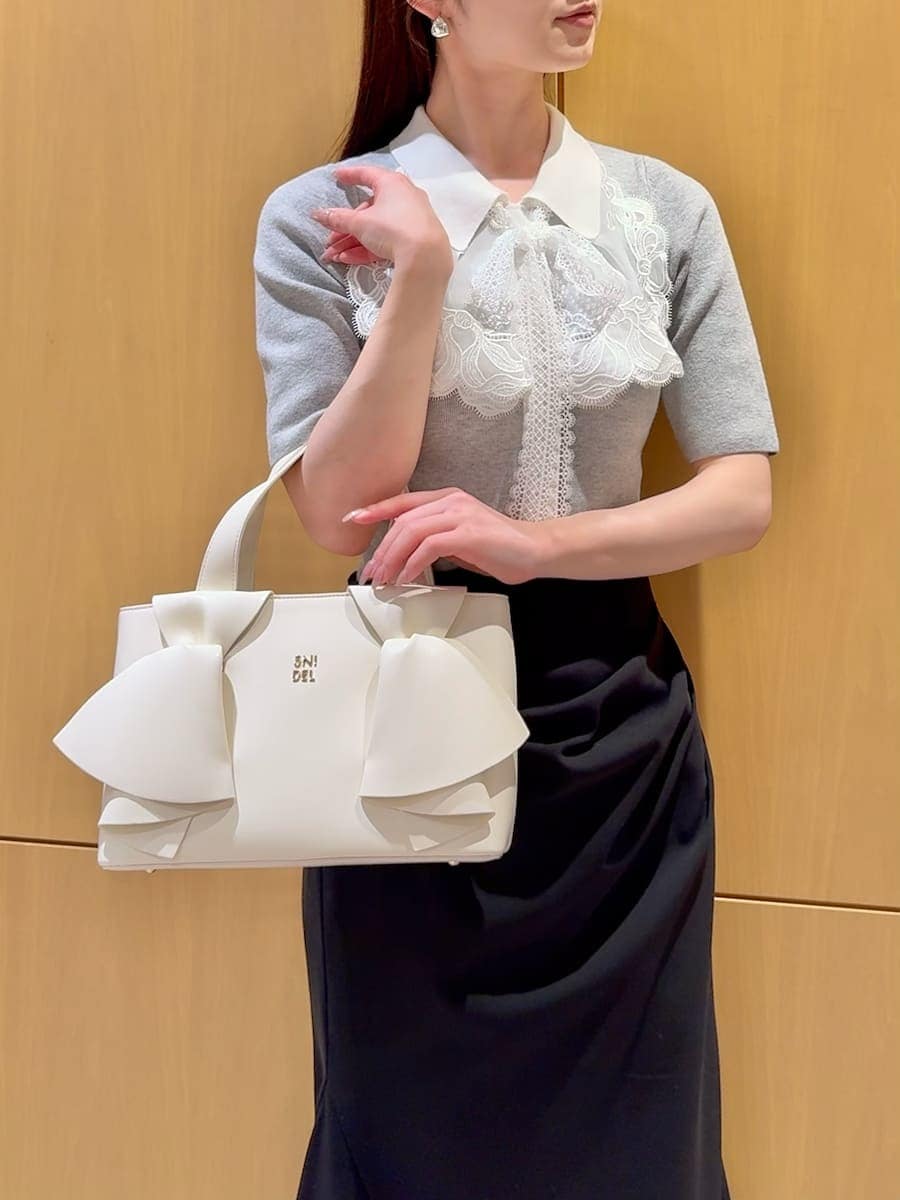 ブラック系のスカート、グレー系のニット/セーター、ホワイト系のハンドバッグを着用したレディースの春コーディネートの6枚目の写真