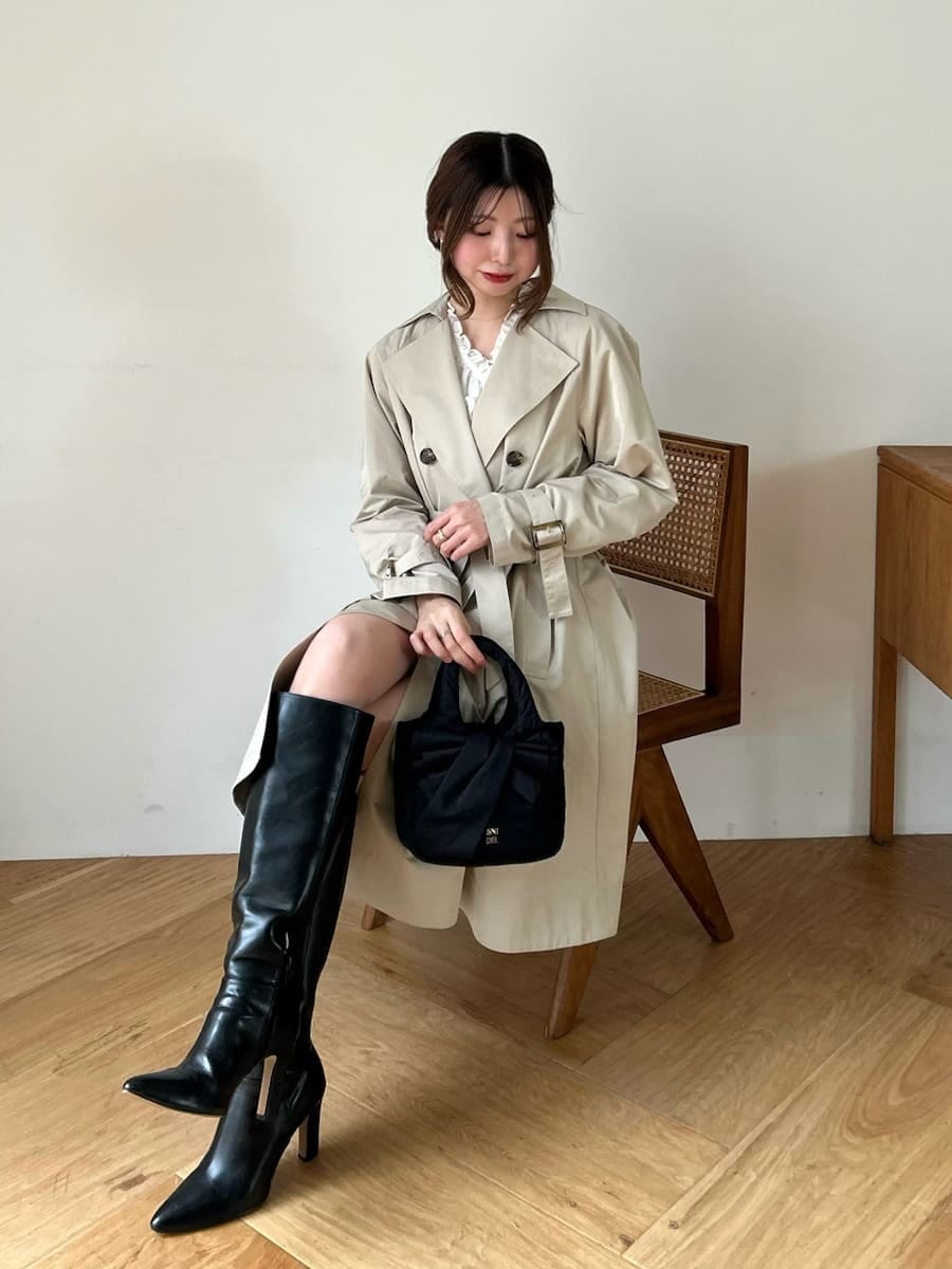 ブラック系のブーツ、ホワイト系のその他トップス、ベージュ系のトレンチコートを着用したレディースの春コーディネートの3枚目の写真