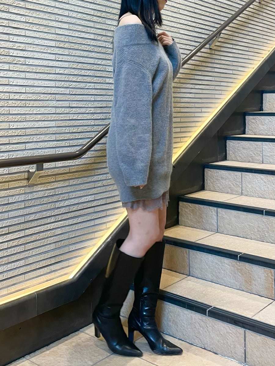 グレー系のワンピース、ブラック系のブーツ、ホワイト系のチェスターコートを着用したレディースの冬コーディネートの6枚目の写真