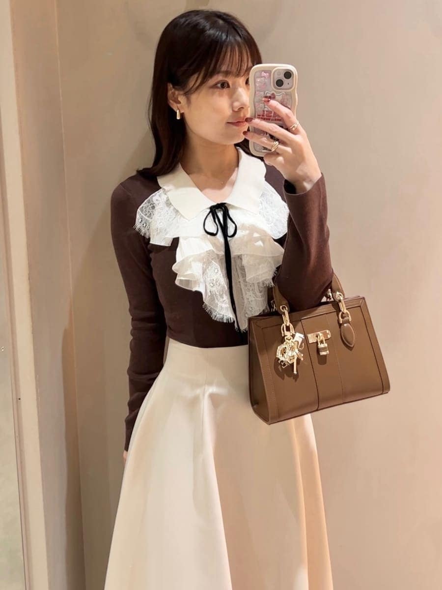 レッド系のブーツ、ブラウン系のニット/セーター、ブラウン系のハンドバッグを着用したレディースの冬コーディネートの6枚目の写真