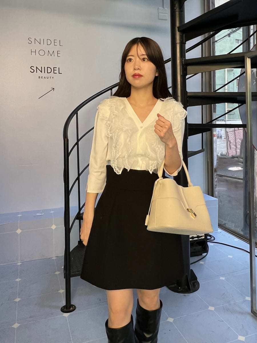 ブラック系のピーコート、ブラック系のスカート、ホワイト系のニット/セーターを着用したレディースの冬コーディネートの5枚目の写真