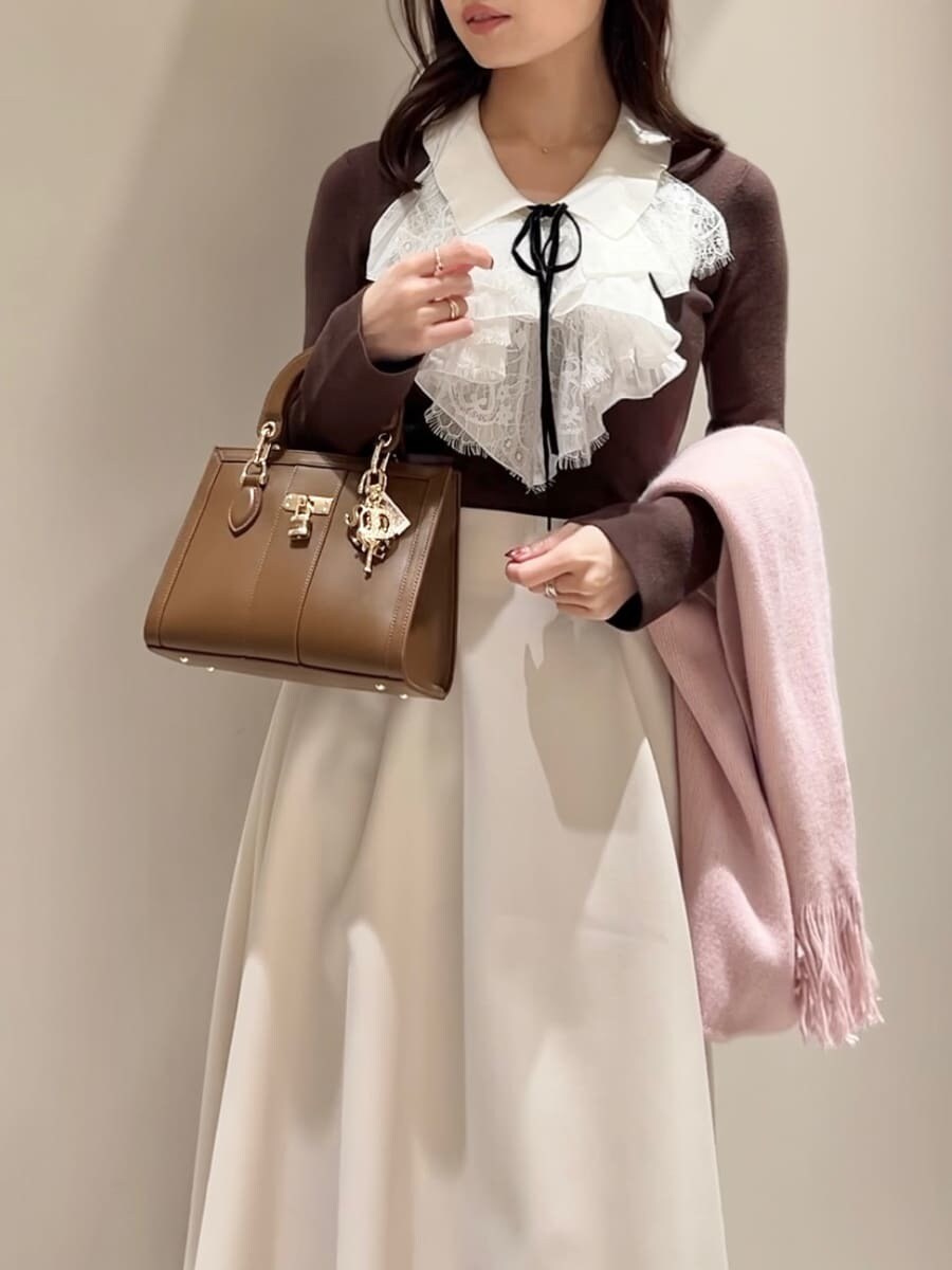 レッド系のブーツ、ブラウン系のニット/セーター、ブラウン系のハンドバッグを着用したレディースの冬コーディネートの4枚目の写真