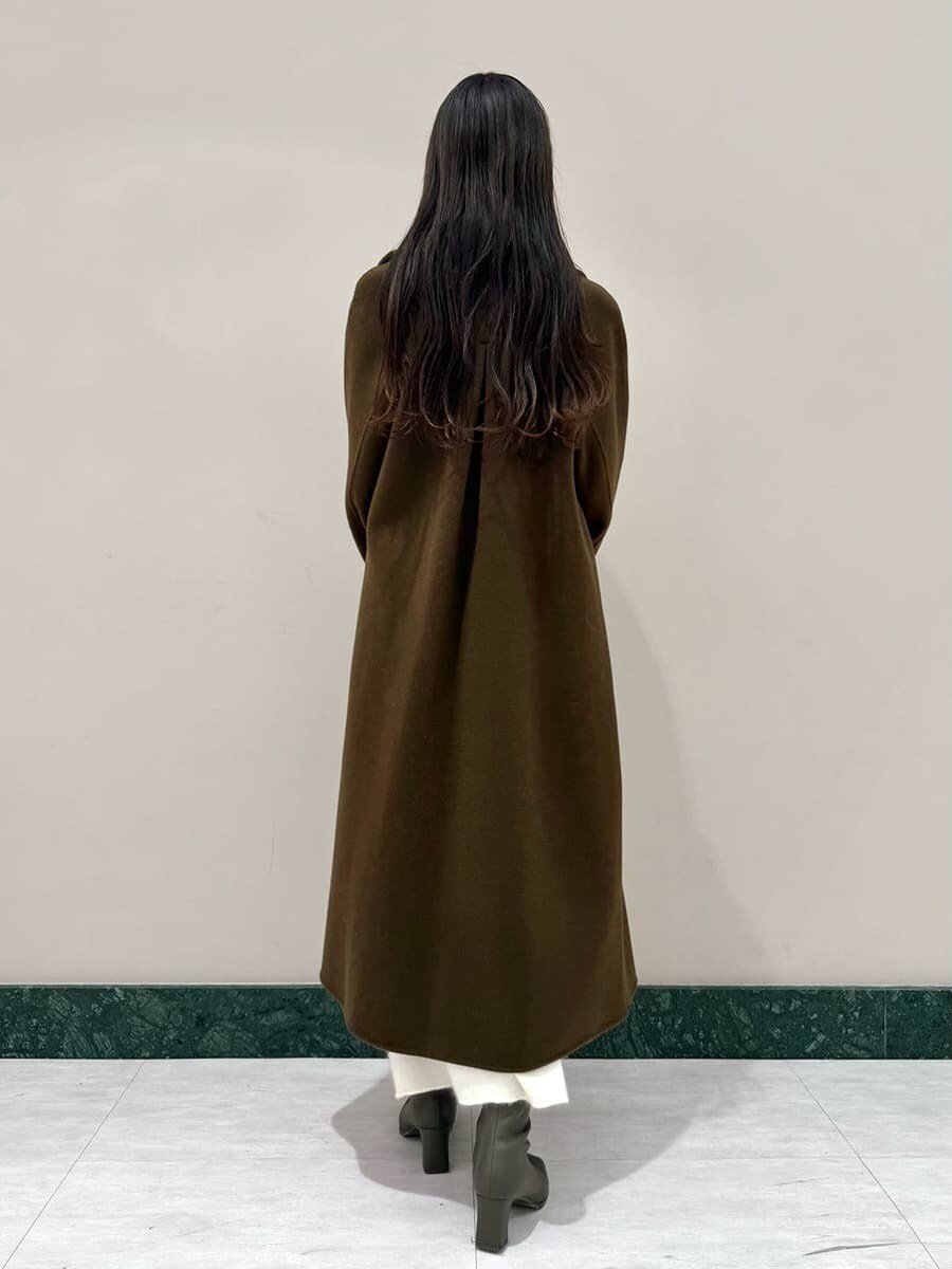 ホワイト系のワンピース、ブラック系のハンドバッグ、ブラウン系のチェスターコートを着用したレディースの冬コーディネートの2枚目の写真