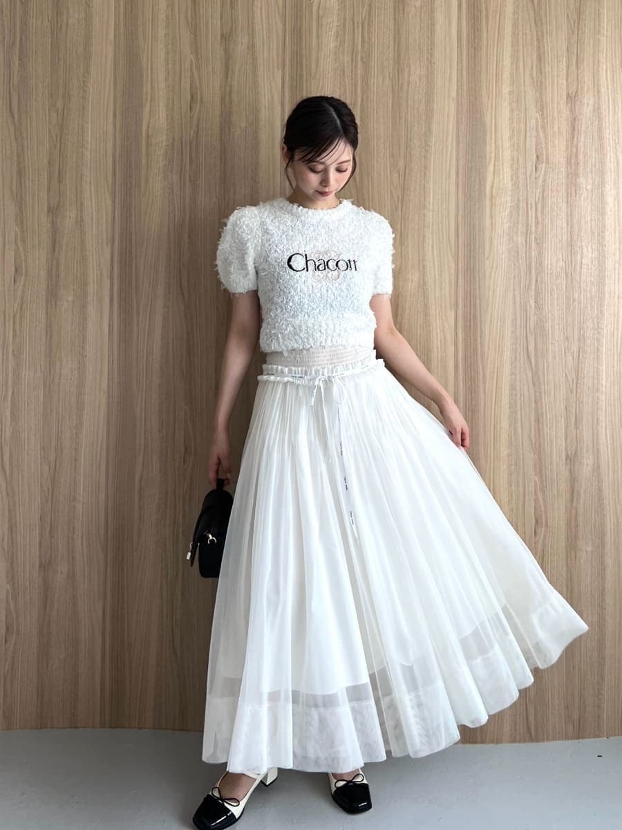 ホワイト系のニット/セーター、ホワイト系のスカート、ブラック系のハンドバッグを着用したレディースの夏コーディネートの3枚目の写真