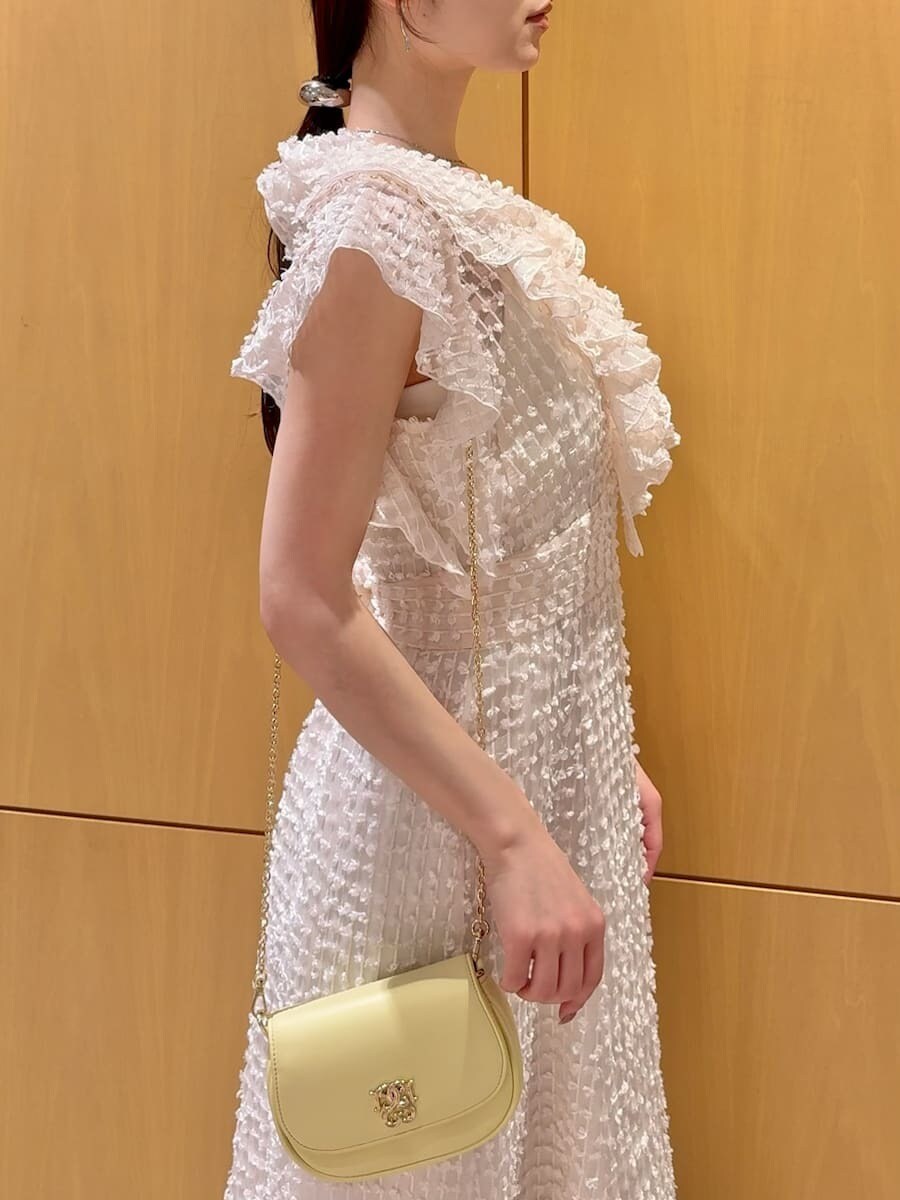 ホワイト系のドレス、イエロー系のパンプス、イエロー系のショルダーバッグを着用したレディースの春コーディネートの6枚目の写真