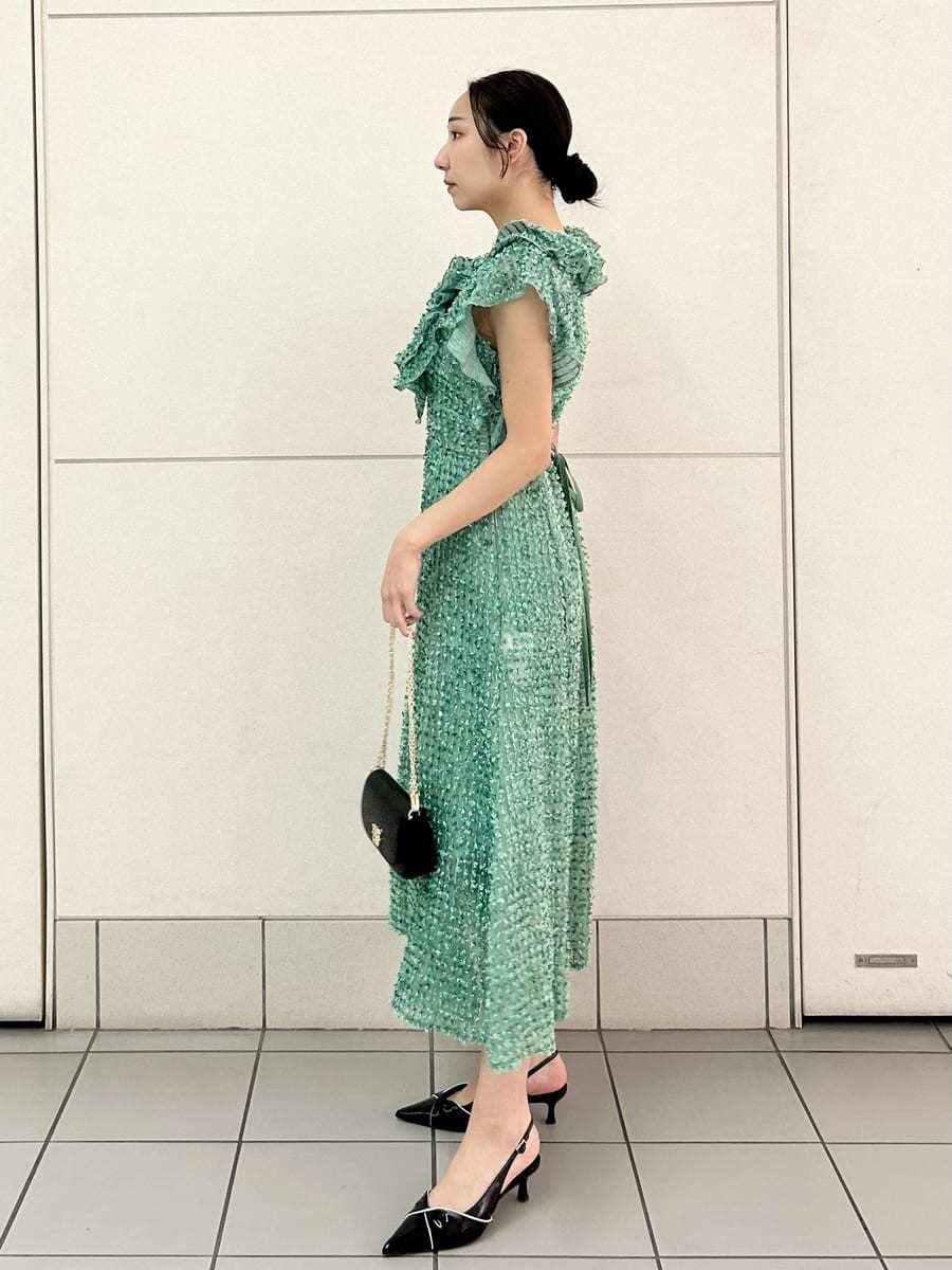 グリーン系のドレス、ブラック系のパンプス、ブラック系のショルダーバッグを着用したレディースの春コーディネートの3枚目の写真