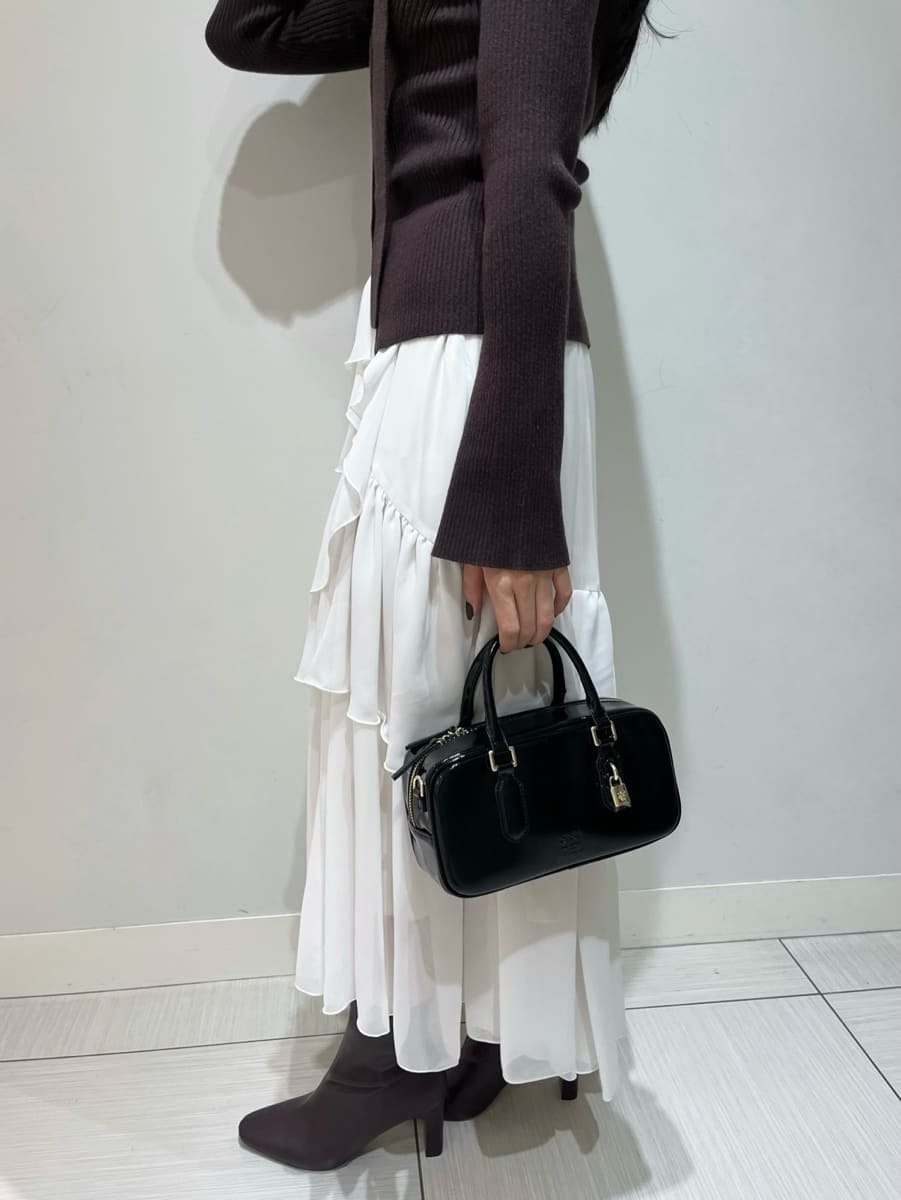 ブラウン系のニット/セーター、ホワイト系のスカート、ブラック系のボストンバッグを着用したレディースの秋コーディネートの6枚目の写真