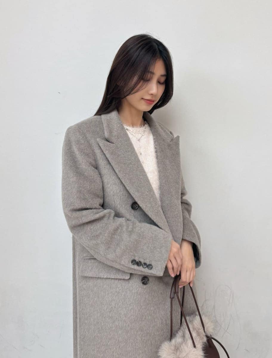 レッド系のブーツ、グレー系のチェスターコート、ホワイト系のスカートを着用したレディースの冬コーディネートの5枚目の写真