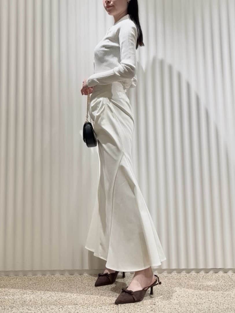 ベージュ系のトレンチコート、ホワイト系のスカート、ブラウン系のパンプスを着用したレディースの冬コーディネートの6枚目の写真