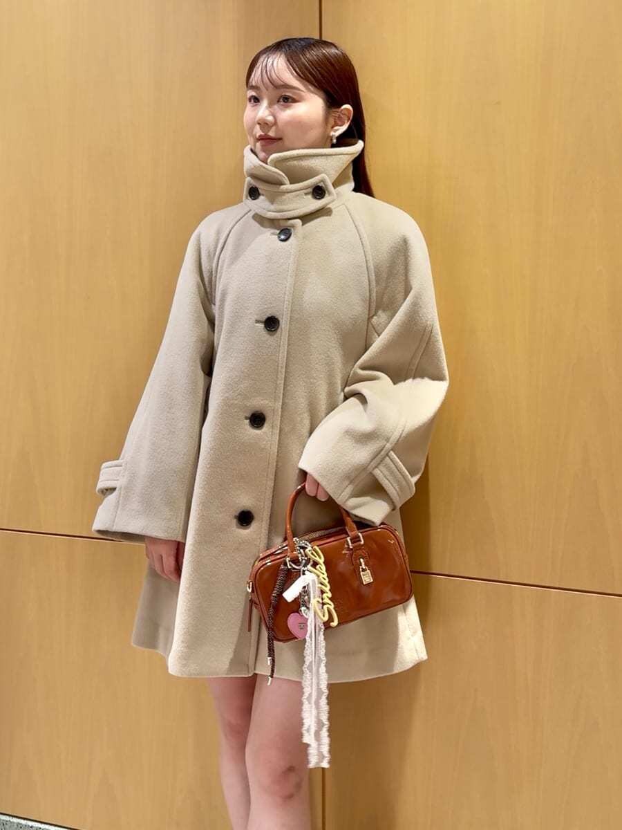 ベージュ系のステンカラーコート、ブルー系のその他トップス、ブラウン系のボストンバッグを着用したレディースの秋コーディネートの2枚目の写真