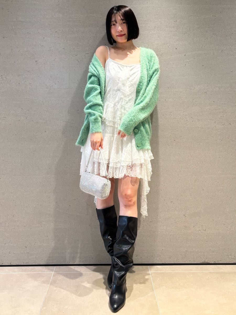 ホワイト系のワンピース、グリーン系のカーディガン/ボレロ、ブラック系のブーツを着用したレディースの冬コーディネートの2枚目の写真