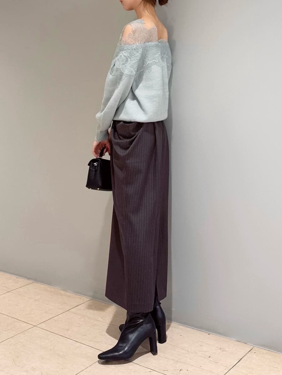 グリーン系のニット/セーター、グレー系のスカート、ブラック系のショルダーバッグを着用したレディースの秋コーディネートの2枚目の写真