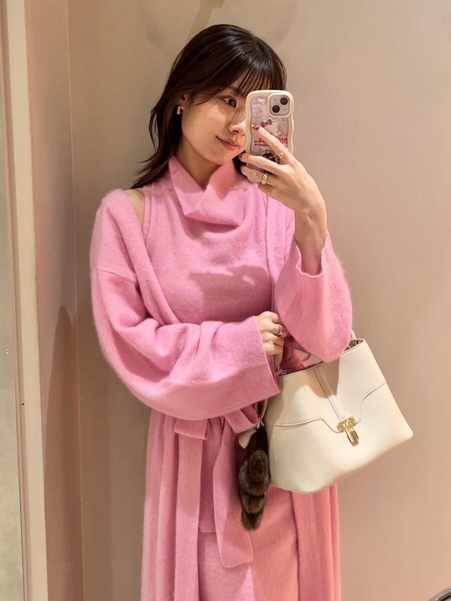 レッド系のブーツ、ピンク系のチェスターコート、ピンク系のワンピースを着用したレディースの冬コーディネートの7枚目の写真