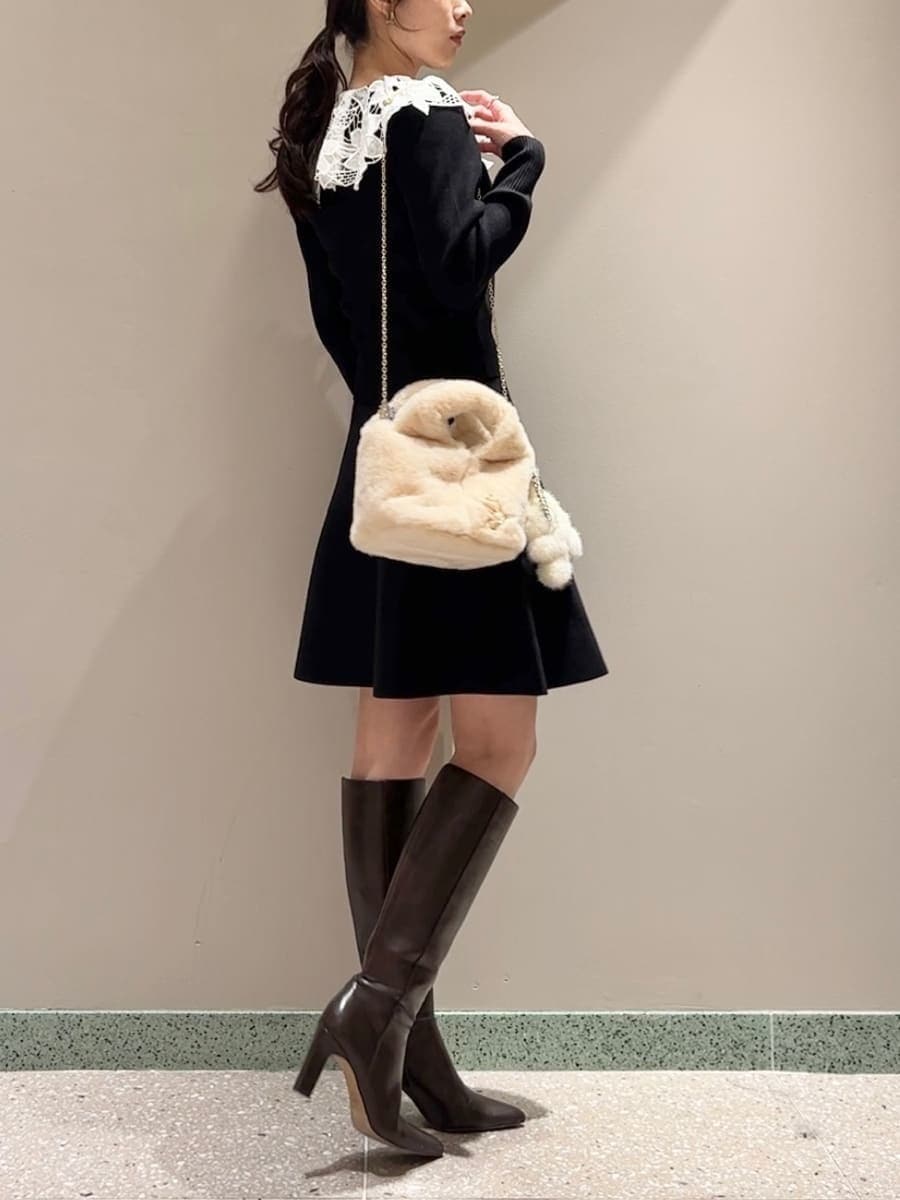 ホワイト系のステンカラーコート、イエロー系のハンドバッグ、ブラック系のワンピースを着用したレディースの冬コーディネートの7枚目の写真