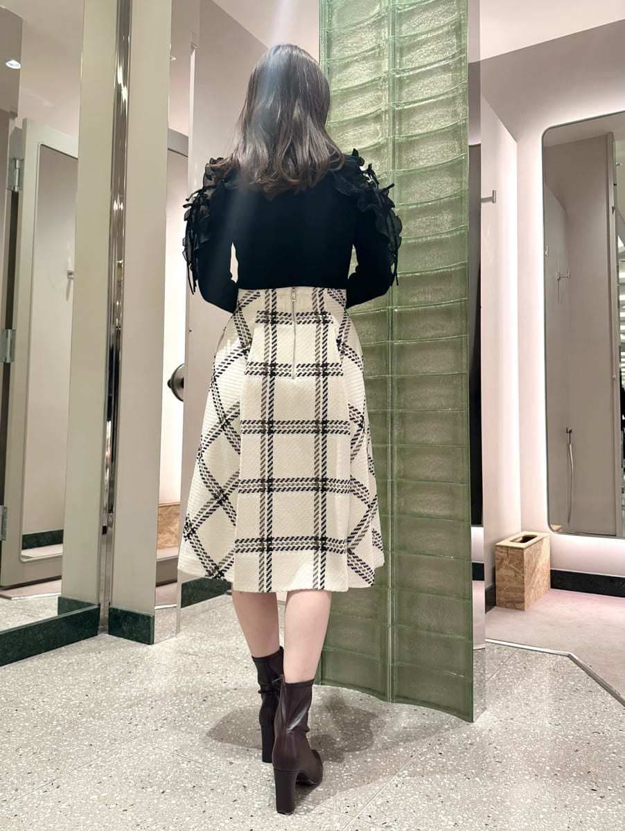 ブラック系のニット/セーター、ホワイト系のスカート、レッド系のブーツを着用したレディースの秋コーディネートの4枚目の写真