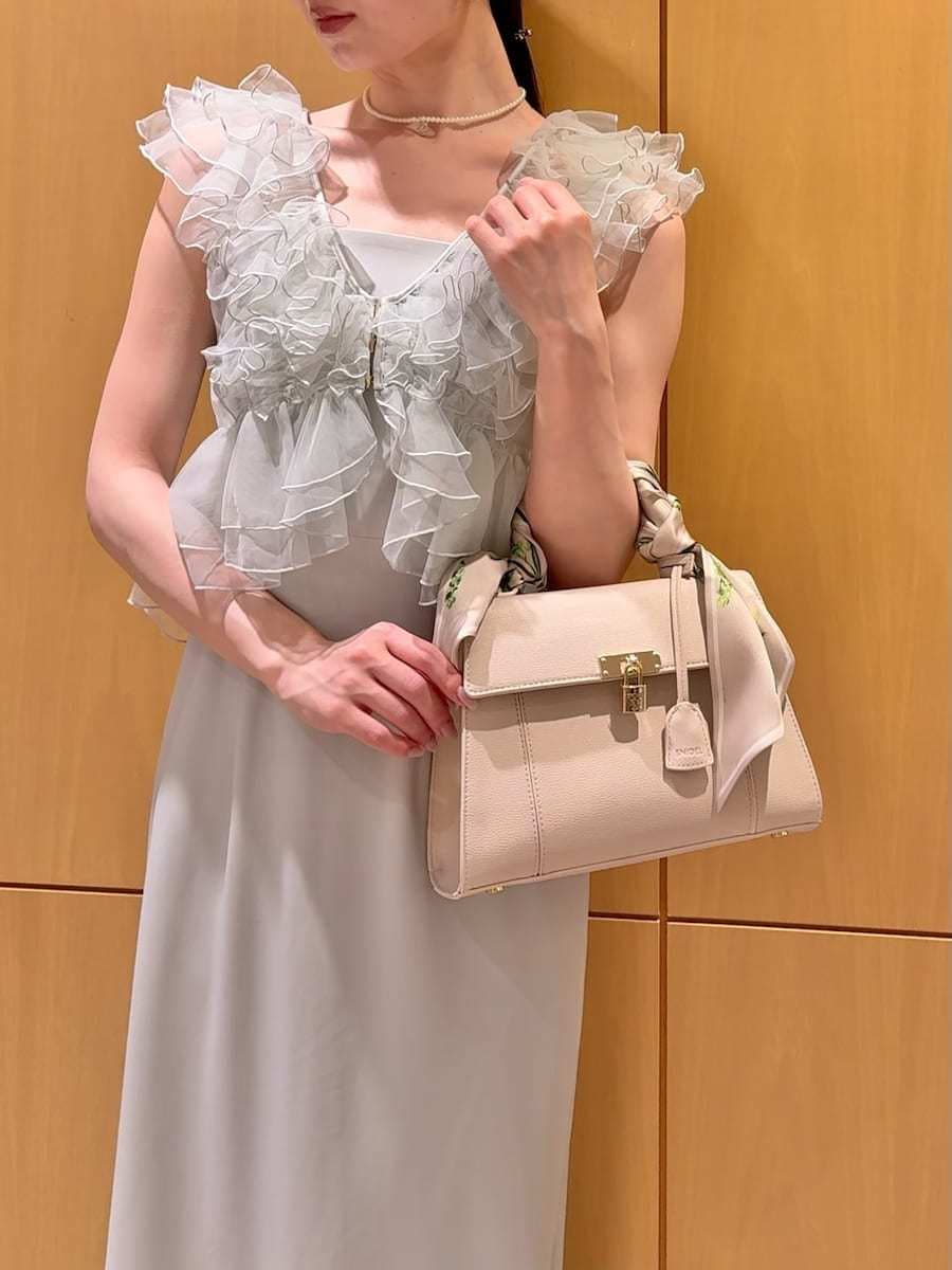 ホワイト系のハンドバッグ、グリーン系のドレス、ホワイト系のネックレスを着用したレディースの春コーディネートの6枚目の写真