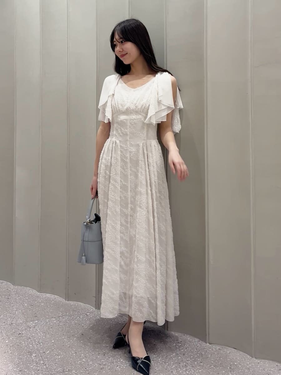 ブルー系のショルダーバッグ、ホワイト系のワンピース、ブラック系のパンプスを着用したレディースの春コーディネートの2枚目の写真