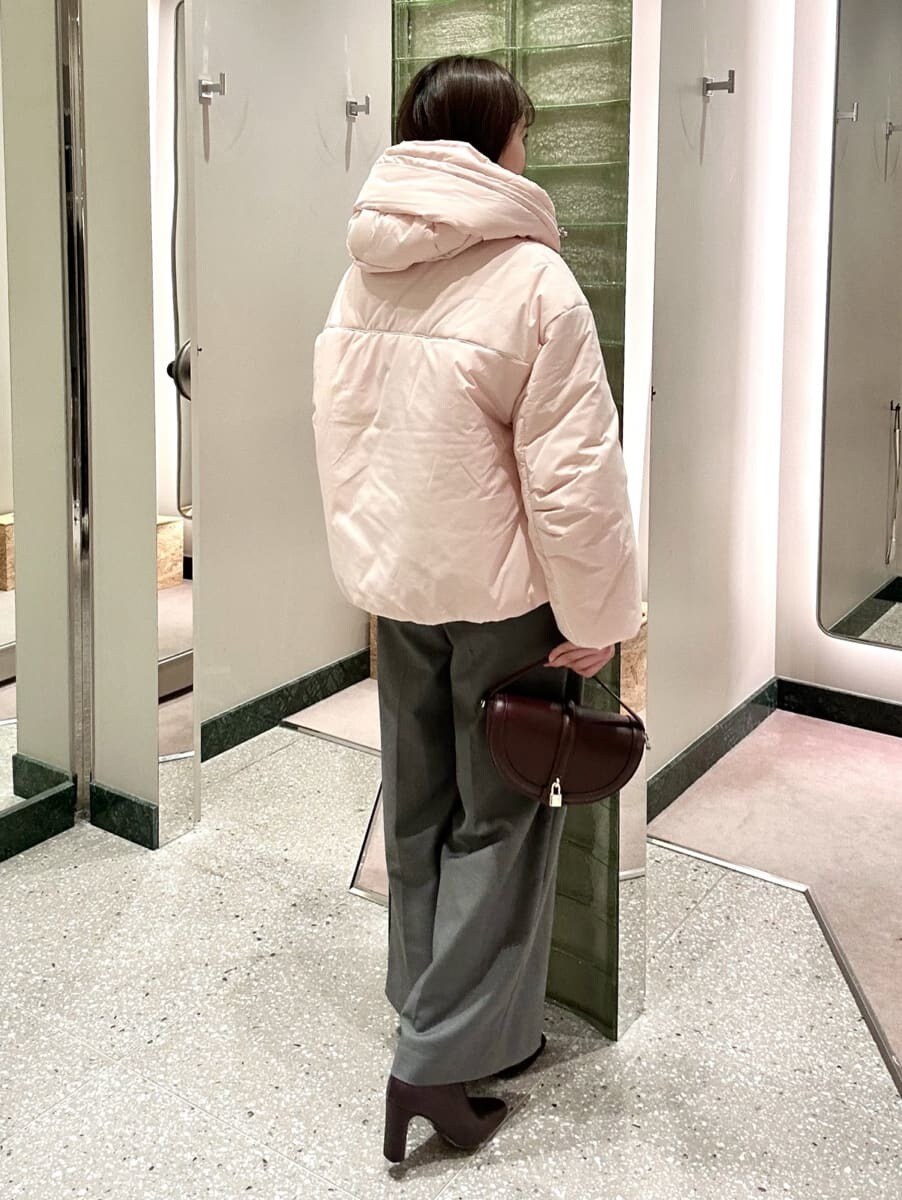 ピンク系のダウンジャケット/コート、ブラック系のニット/セーター、グレー系のスラックスを着用したレディースの秋コーディネートの4枚目の写真