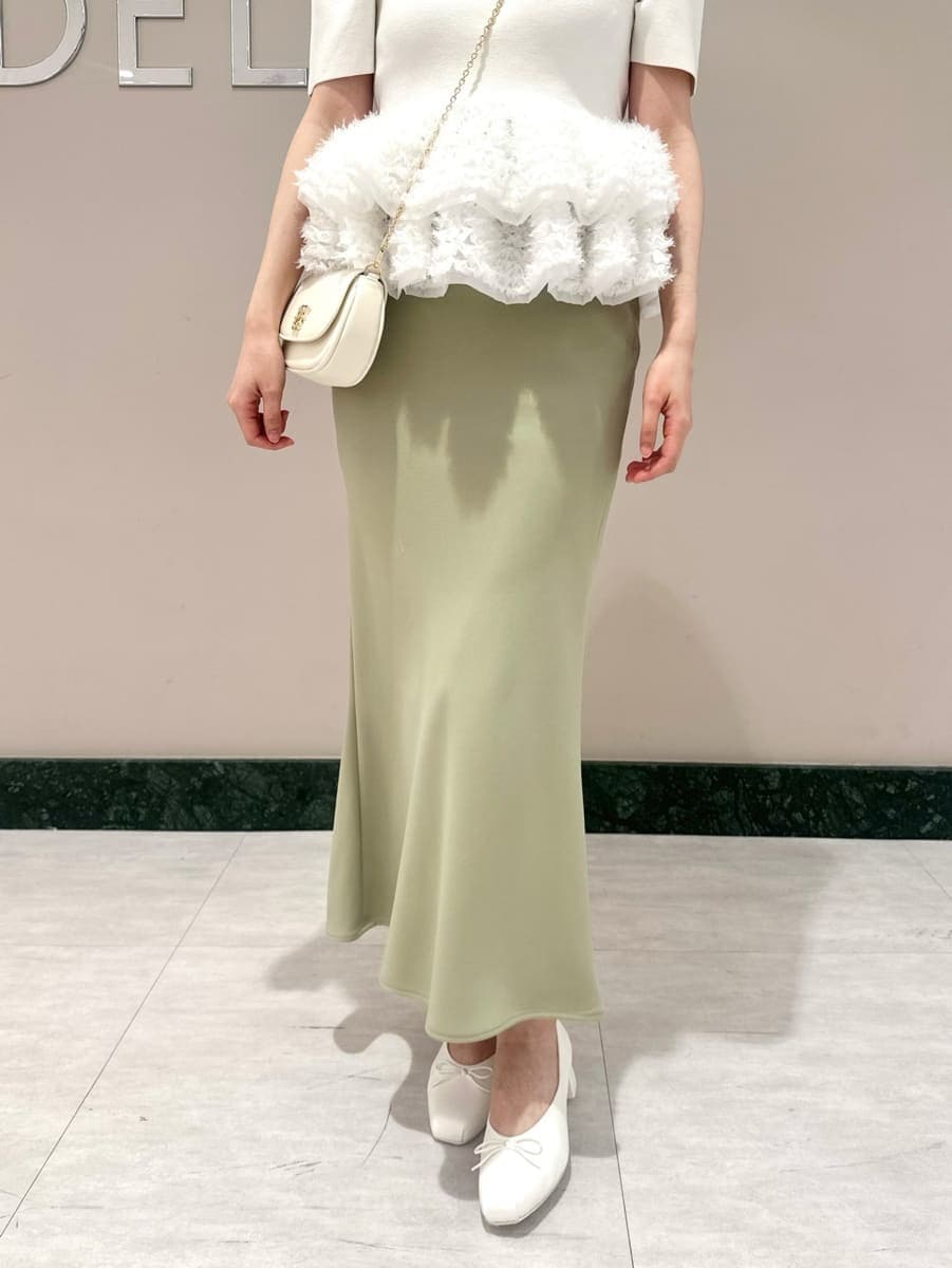 グリーン系のスカート、ホワイト系のニット/セーター、ホワイト系のショルダーバッグを着用したレディースの春コーディネートの3枚目の写真