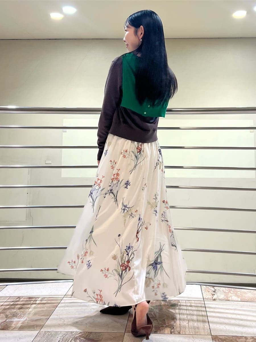 グリーン系のカーディガン/ボレロ、ホワイト系のワンピース、ブラウン系のパンプスを着用したレディースの冬コーディネートの3枚目の写真