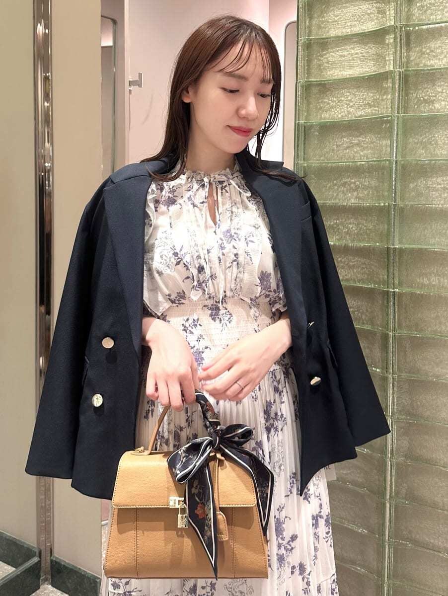 ブルー系のテーラードジャケット、ホワイト系のワンピース、イエロー系のハンドバッグを着用したレディースの秋コーディネートの3枚目の写真