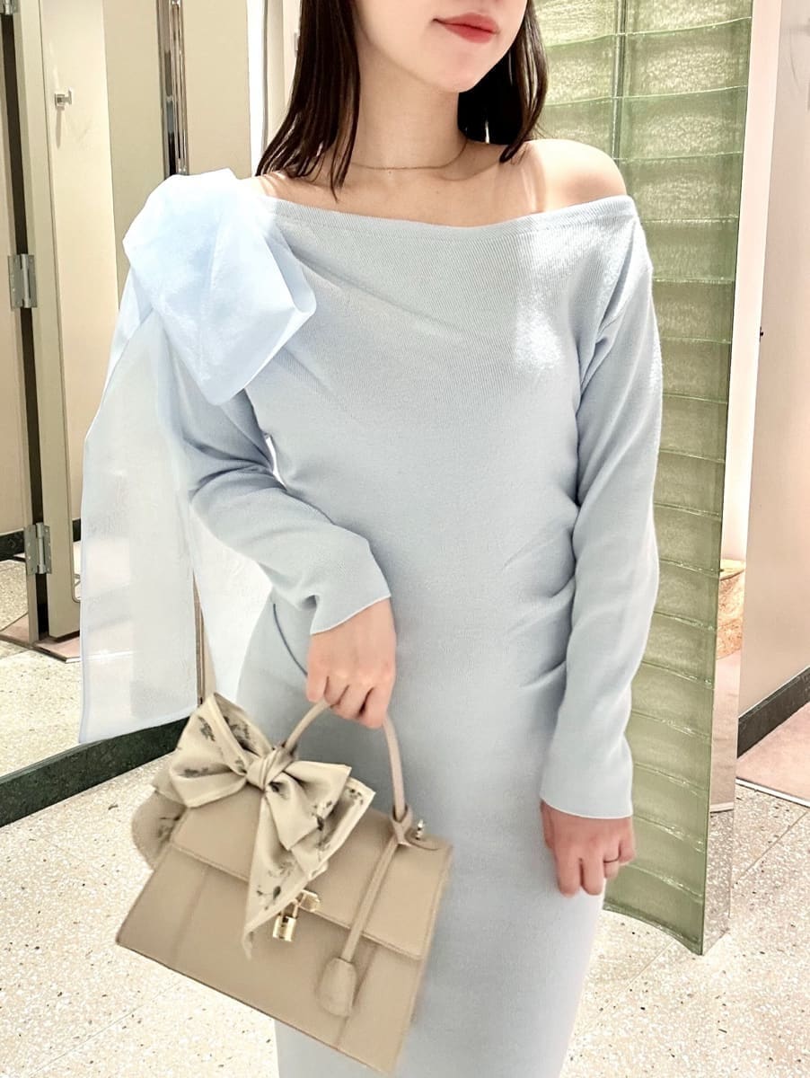 ブルー系のワンピース、その他のパンプス、ベージュ系のハンドバッグを着用したレディースの冬コーディネートの2枚目の写真