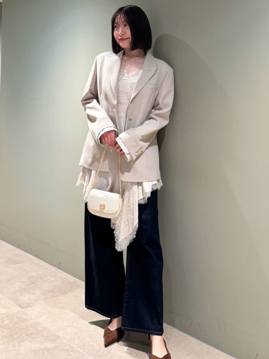 ベージュ系のテーラードジャケット、ブルー系のデニムパンツ、ホワイト系のキャミソールを着用したレディースの春コーディネートの2枚目の写真