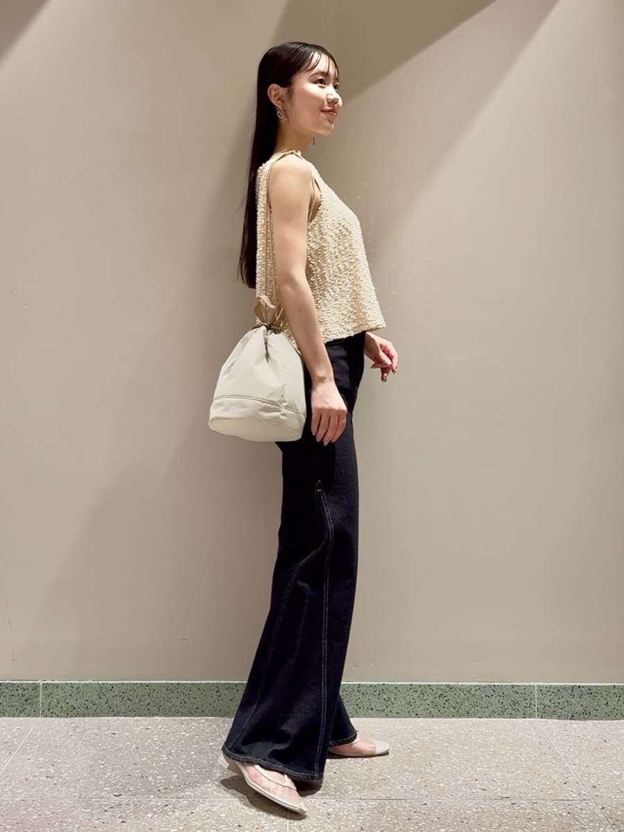 ホワイト系のタンクトップ、ブルー系のデニムパンツ、ベージュ系のハンドバッグを着用したレディースの夏コーディネートの3枚目の写真