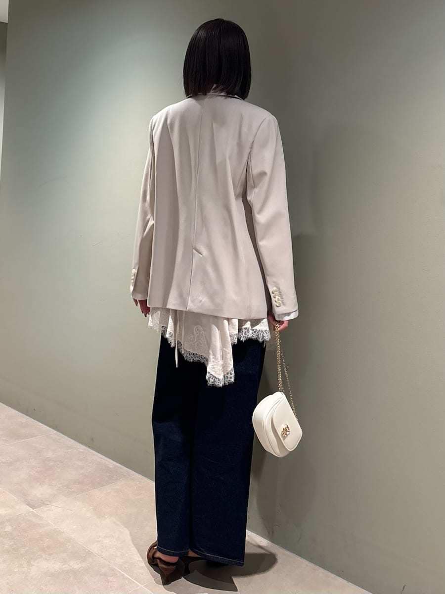 ベージュ系のテーラードジャケット、ブルー系のデニムパンツ、ホワイト系のキャミソールを着用したレディースの春コーディネートの5枚目の写真