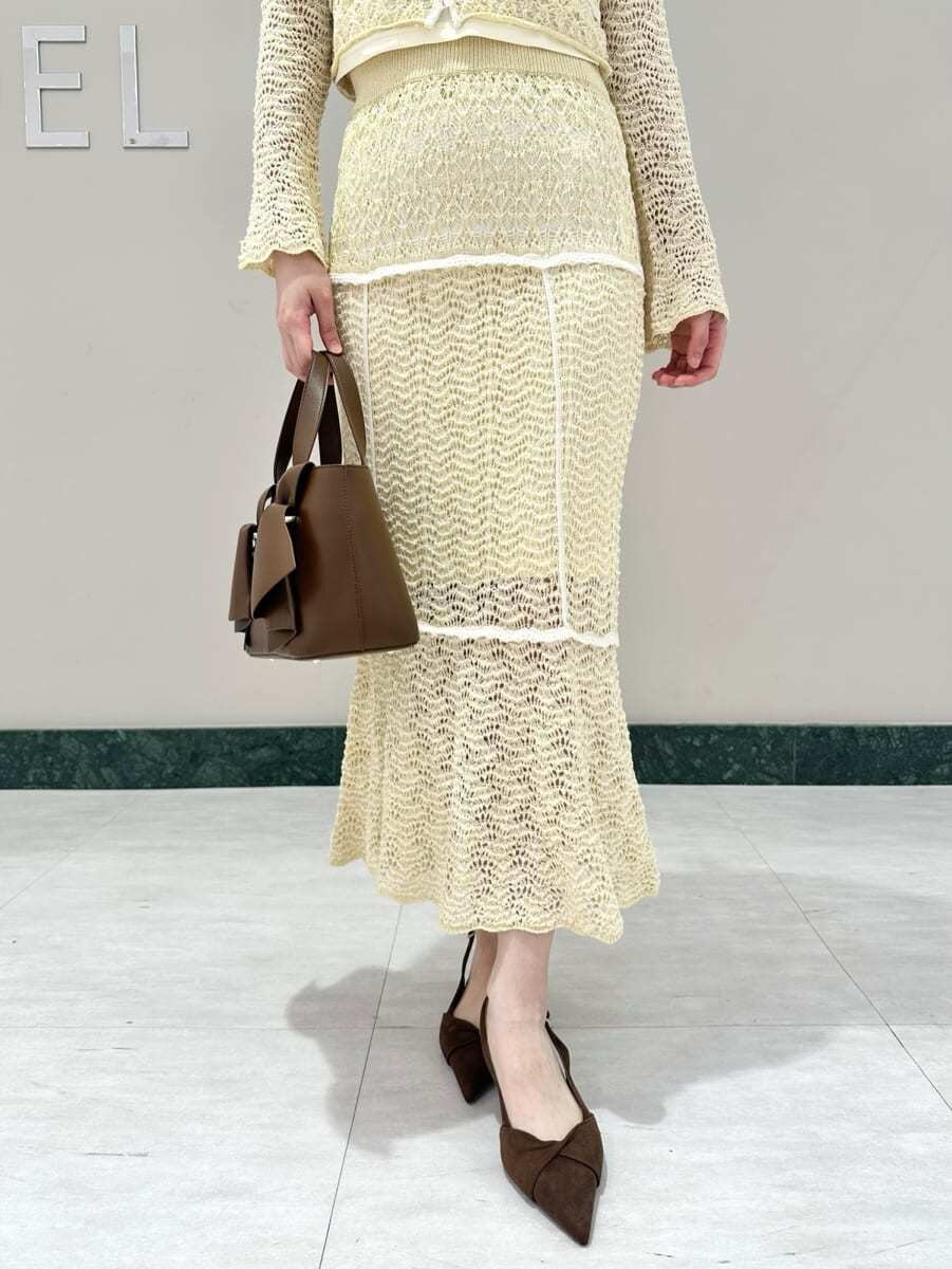 イエロー系のスカート、ブラウン系のパンプス、ブラウン系のハンドバッグを着用したレディースの春コーディネートの3枚目の写真