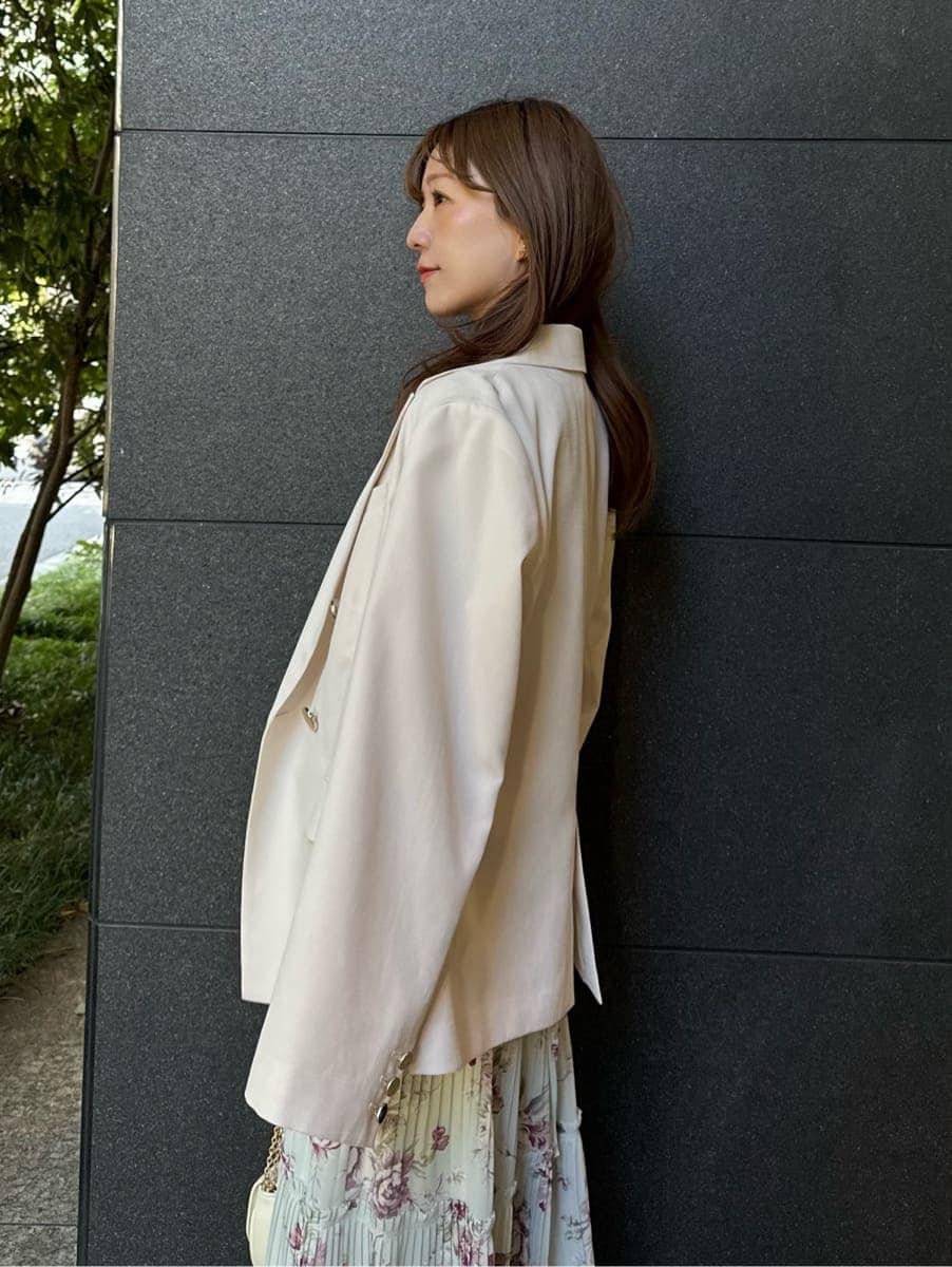 グリーン系のワンピース、ホワイト系のショルダーバッグ、ゴールド系のイヤリングを着用したレディースの春コーディネートの4枚目の写真