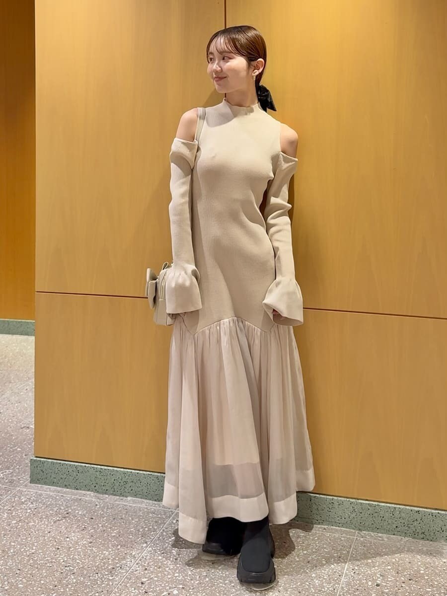 グレー系のチェスターコート、ホワイト系のワンピース、ブラック系のブーツを着用したレディースの冬コーディネートの4枚目の写真