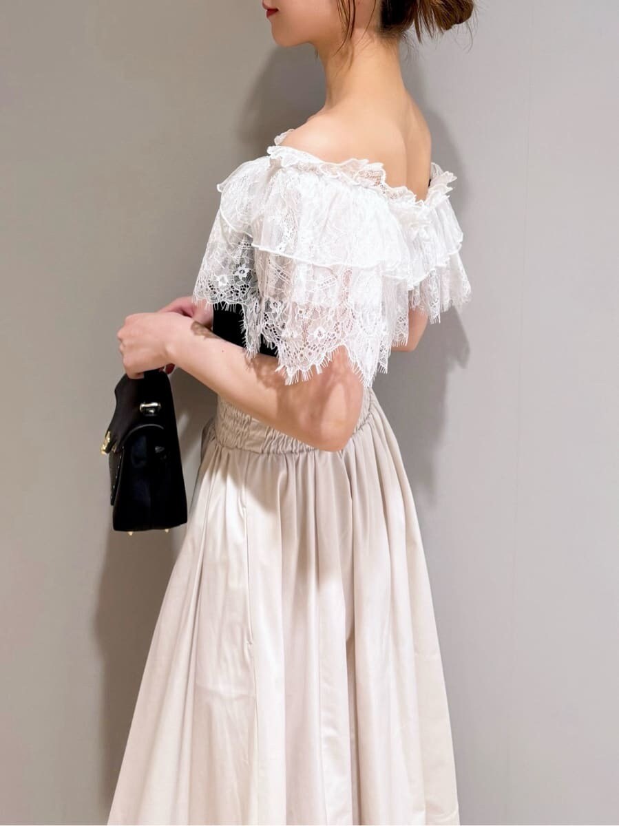 ブラック系のニット/セーター、ホワイト系のスカート、ブラック系のショルダーバッグを着用したレディースの夏コーディネートの4枚目の写真