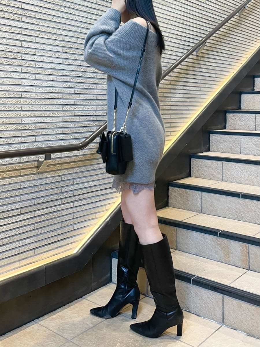 グレー系のワンピース、ブラック系のブーツ、ホワイト系のチェスターコートを着用したレディースの冬コーディネートの4枚目の写真