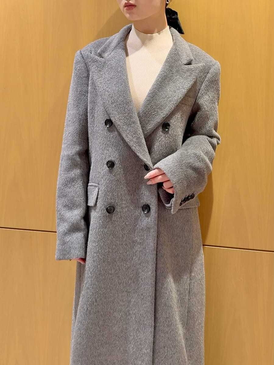 グレー系のチェスターコート、ホワイト系のワンピース、ブラック系のブーツを着用したレディースの冬コーディネートの6枚目の写真