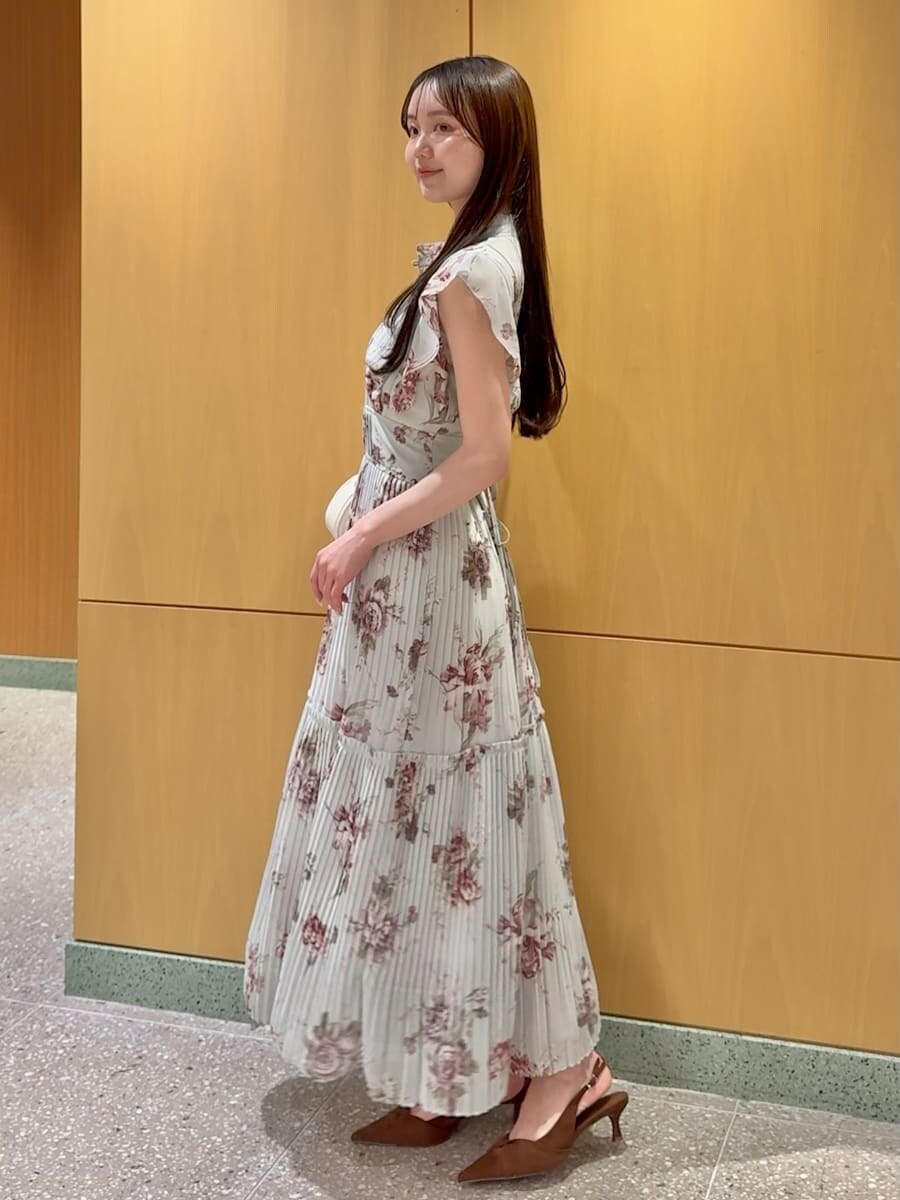 グリーン系のワンピース、ブラウン系のパンプス、ホワイト系のショルダーバッグを着用したレディースの春コーディネートの2枚目の写真