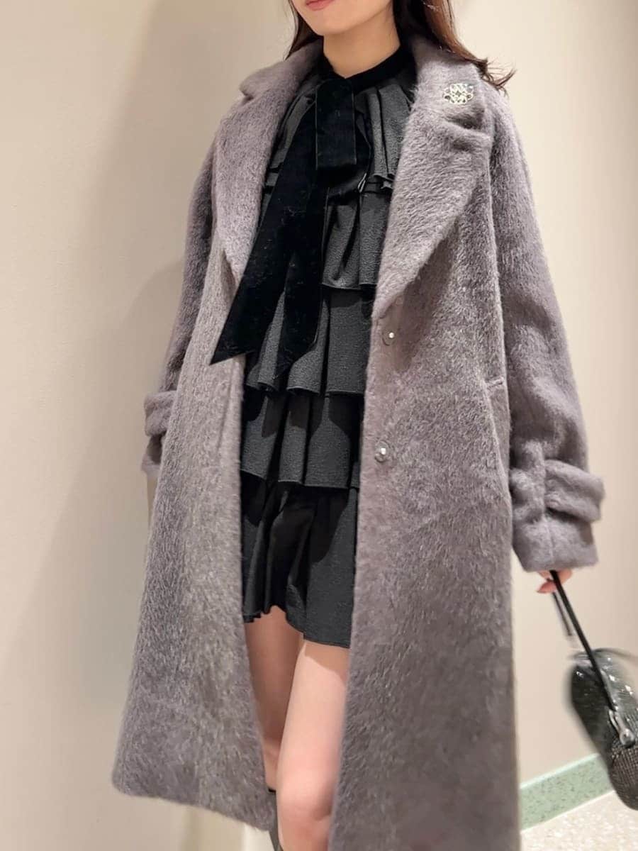 グレー系のブーツ、グレー系のチェスターコート、ブラック系のドレスを着用したレディースの冬コーディネートの5枚目の写真