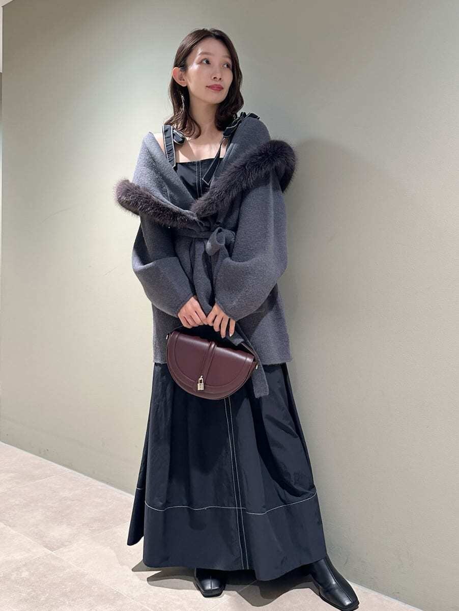 ブラック系のワンピース、ブラウン系のハンドバッグ、ブラック系のブーツを着用したレディースの秋コーディネートの3枚目の写真