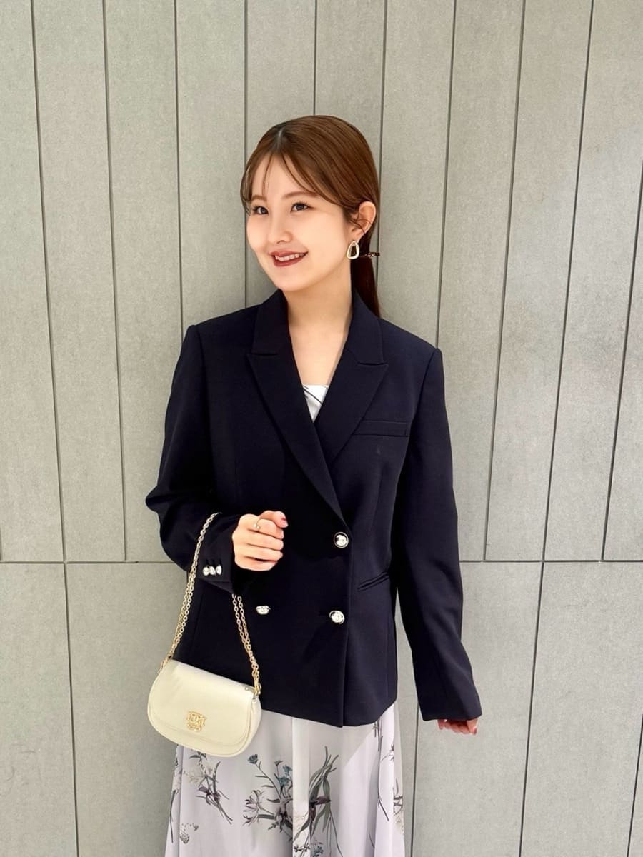 ブルー系のテーラードジャケット、パープル系のワンピース、ホワイト系のショルダーバッグを着用したレディースの春コーディネートの3枚目の写真