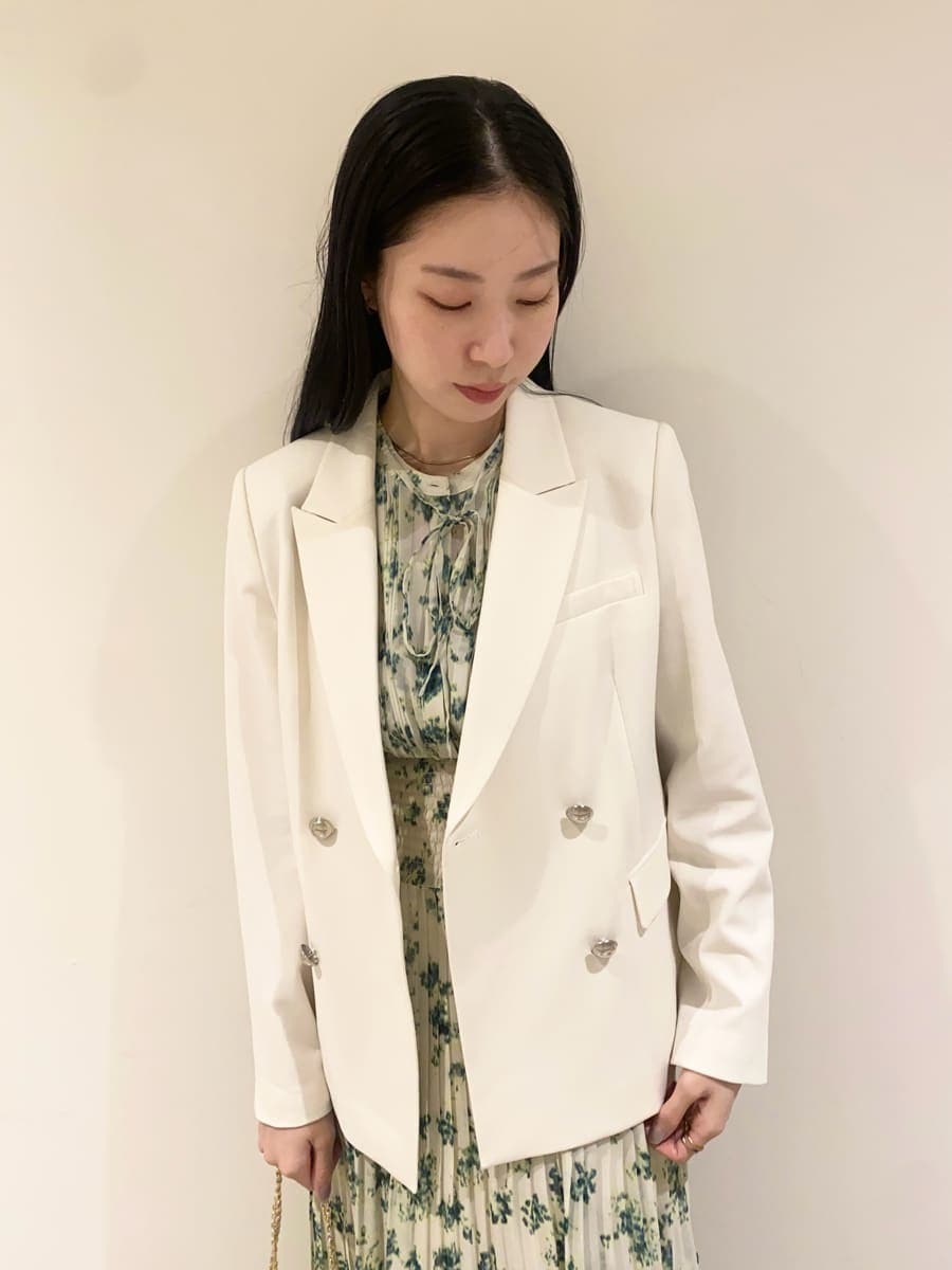 グリーン系のワンピース、ホワイト系のテーラードジャケット、イエロー系のショルダーバッグを着用したレディースの冬コーディネートの2枚目の写真