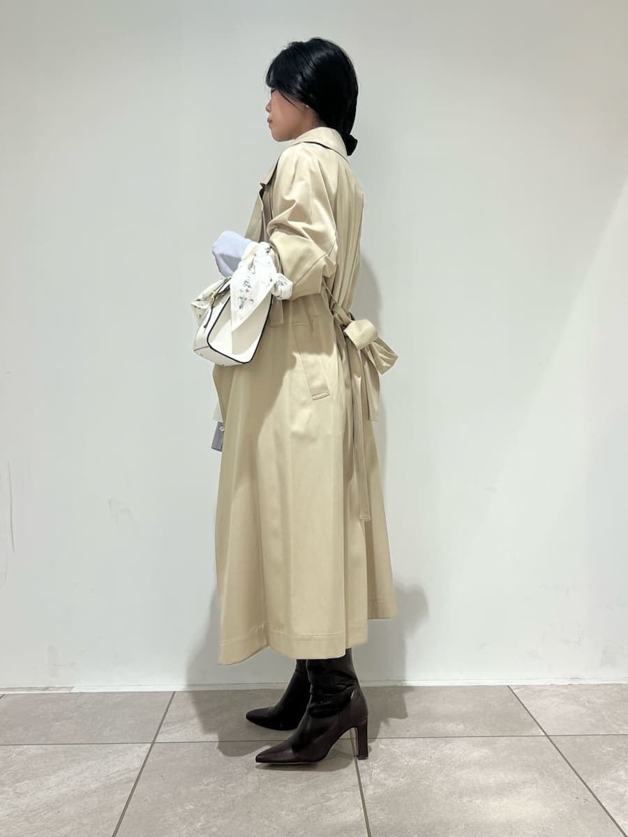 ブラウン系のブーツ、ベージュ系のトレンチコート、ホワイト系のハンドバッグを着用したレディースの冬コーディネートの8枚目の写真