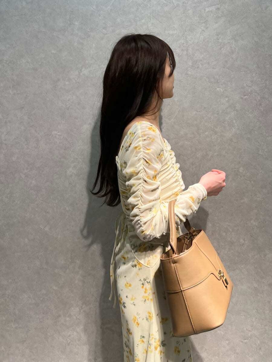 ベージュ系のブーツ、イエロー系のワンピース、イエロー系のハンドバッグを着用したレディースの冬コーディネートの5枚目の写真