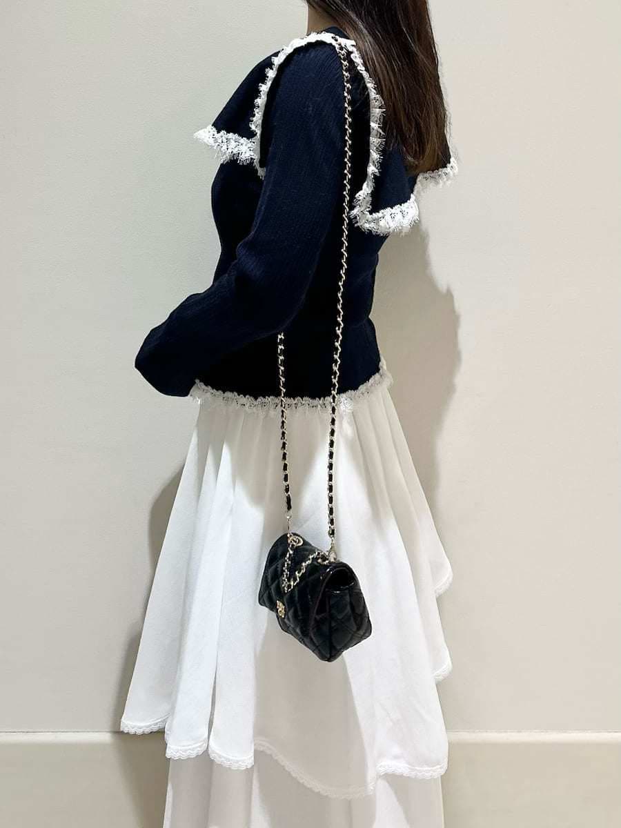 ブラック系のブーツ、ブラック系のショルダーバッグ、ホワイト系のスカートを着用したレディースの冬コーディネートの3枚目の写真