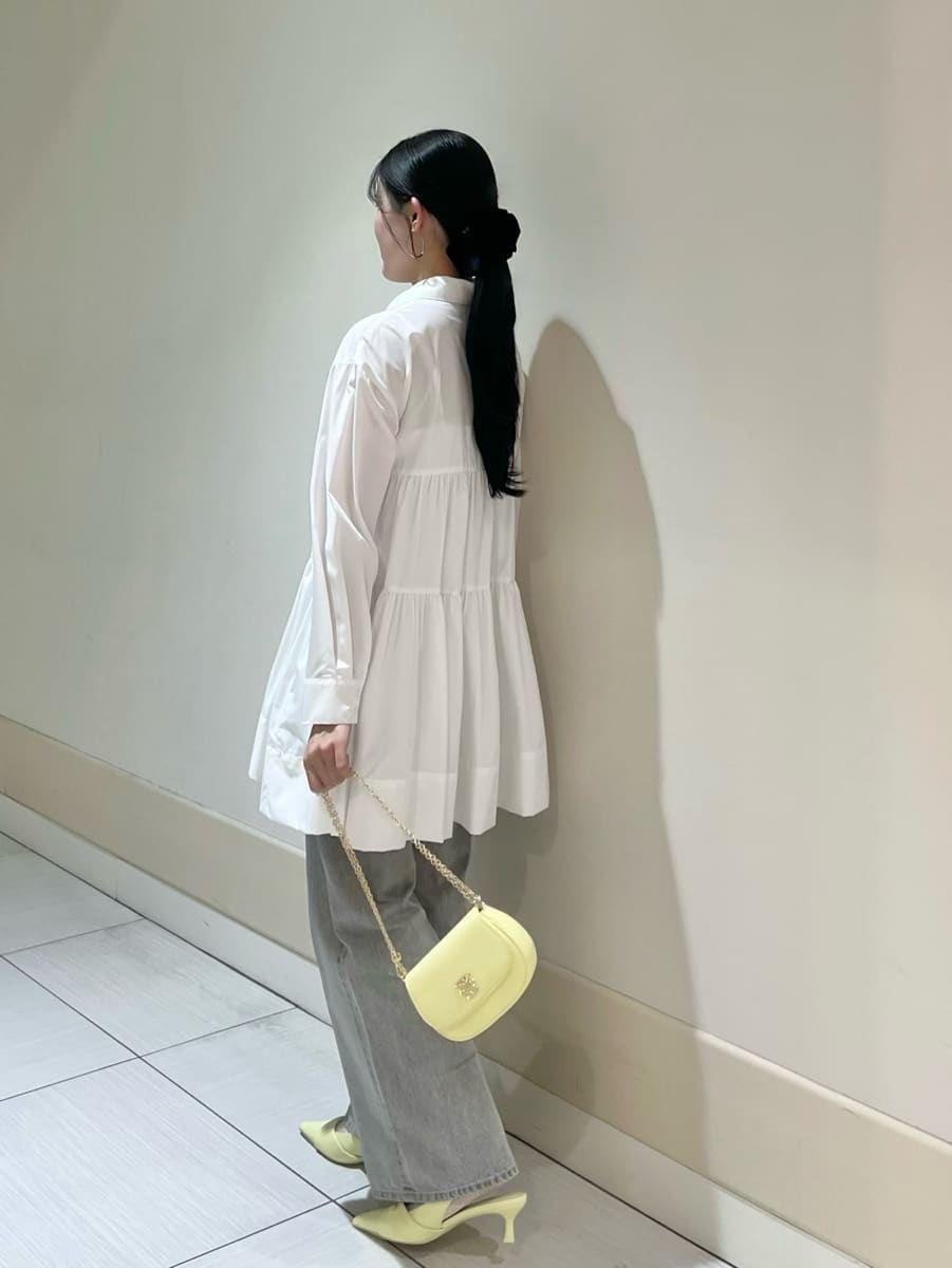 グレー系のデニムパンツ、ホワイト系のワンピース、イエロー系のパンプスを着用したレディースの春コーディネートの2枚目の写真