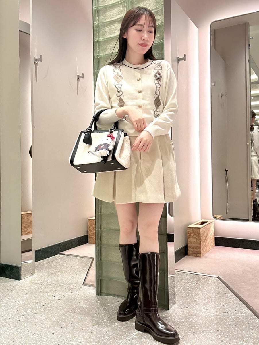 ホワイト系のカーディガン/ボレロ、ホワイト系のスカート、ブラック系のブーツを着用したレディースの秋コーディネートの2枚目の写真