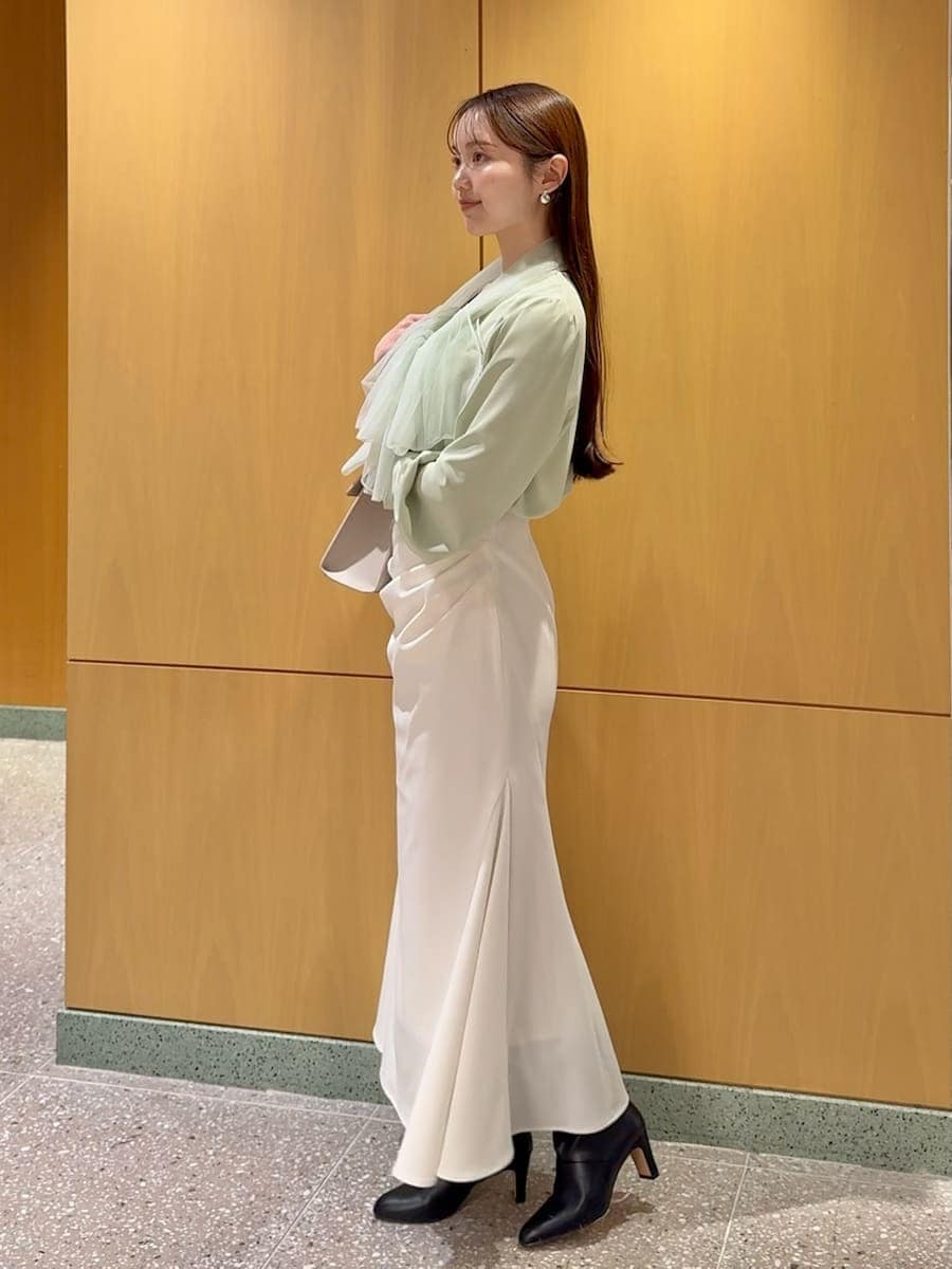 ブラック系のブーツ、ホワイト系のトレンチコート、ホワイト系のスカートを着用したレディースの冬コーディネートの5枚目の写真