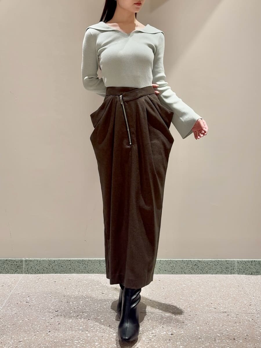 グリーン系のニット/セーター、ブラウン系のスカート、ブラック系のブーツを着用したレディースの秋コーディネートの5枚目の写真