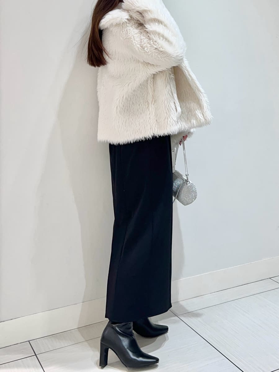 ブラック系のブーツ、ホワイト系のムートンコート、ブラック系のワンピースを着用したレディースの冬コーディネートの4枚目の写真