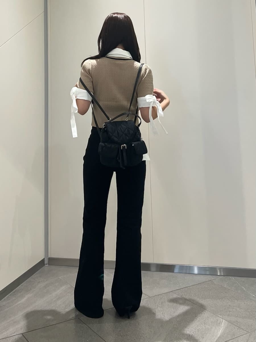 ブラック系のデニムパンツ、ベージュ系のニット/セーター、ブラック系のサンダルを着用したレディースの夏コーディネートの3枚目の写真